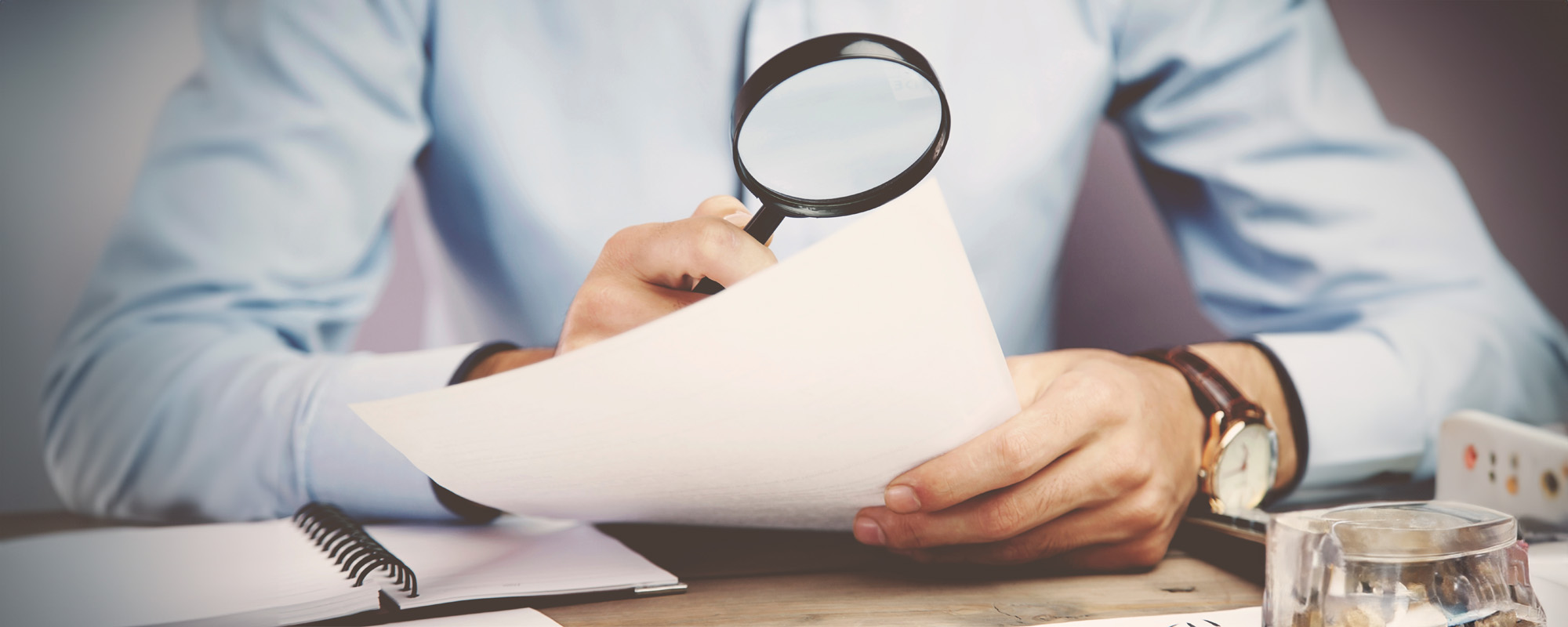 person using magnifying glass to review documents