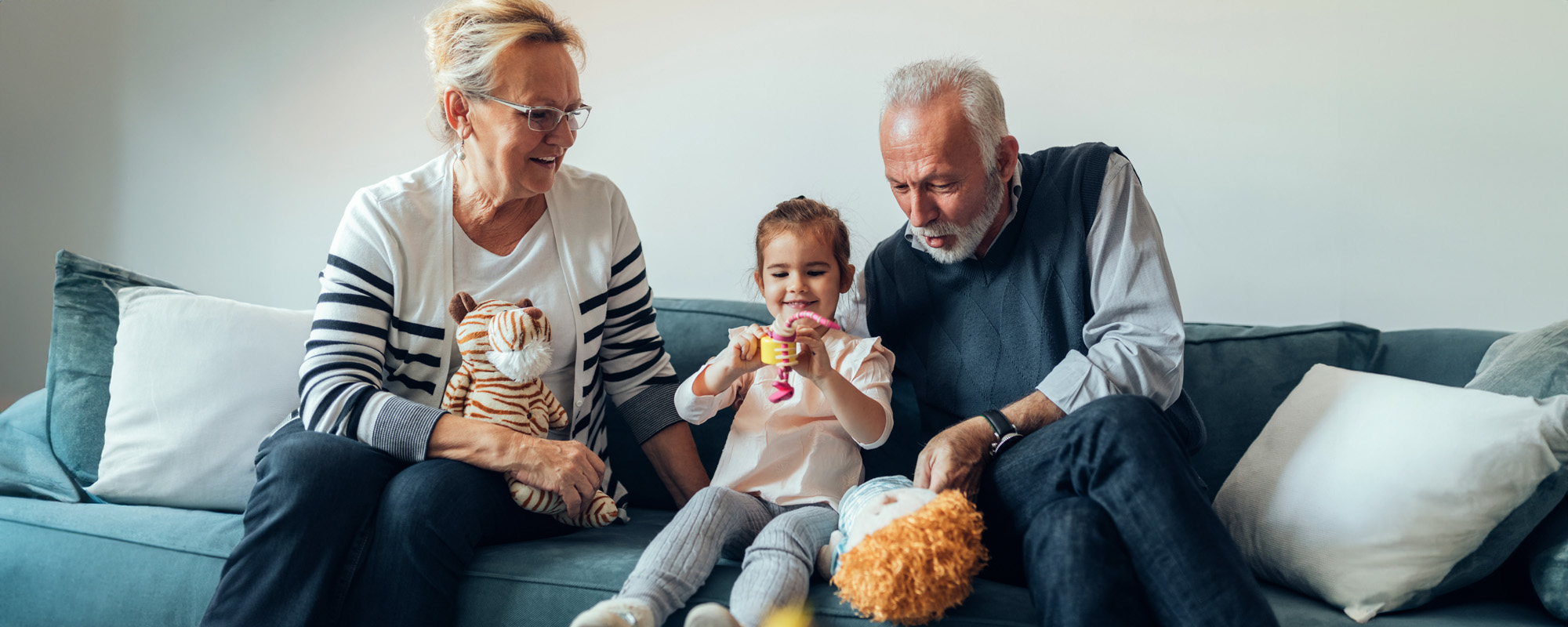 young girl playing on the sofa with her grandparents