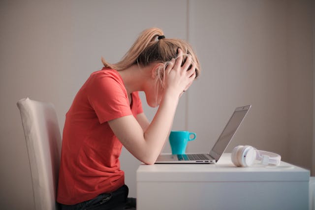 distressed woman sitting at a table with laptop