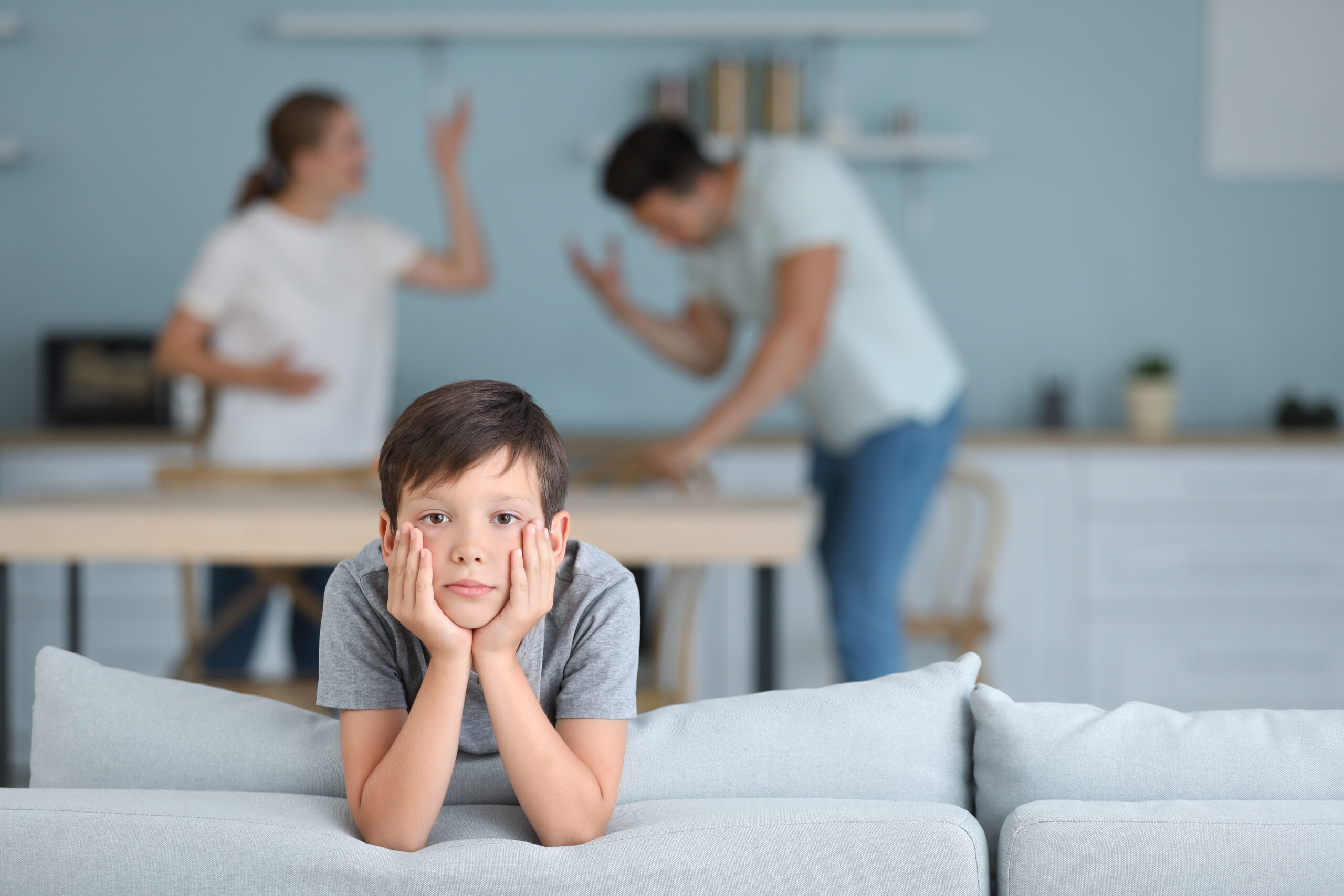 Sad little boy and his quarreling parents at home