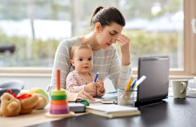 remote job, multi-tasking and family concept - tired mother with baby working at home office